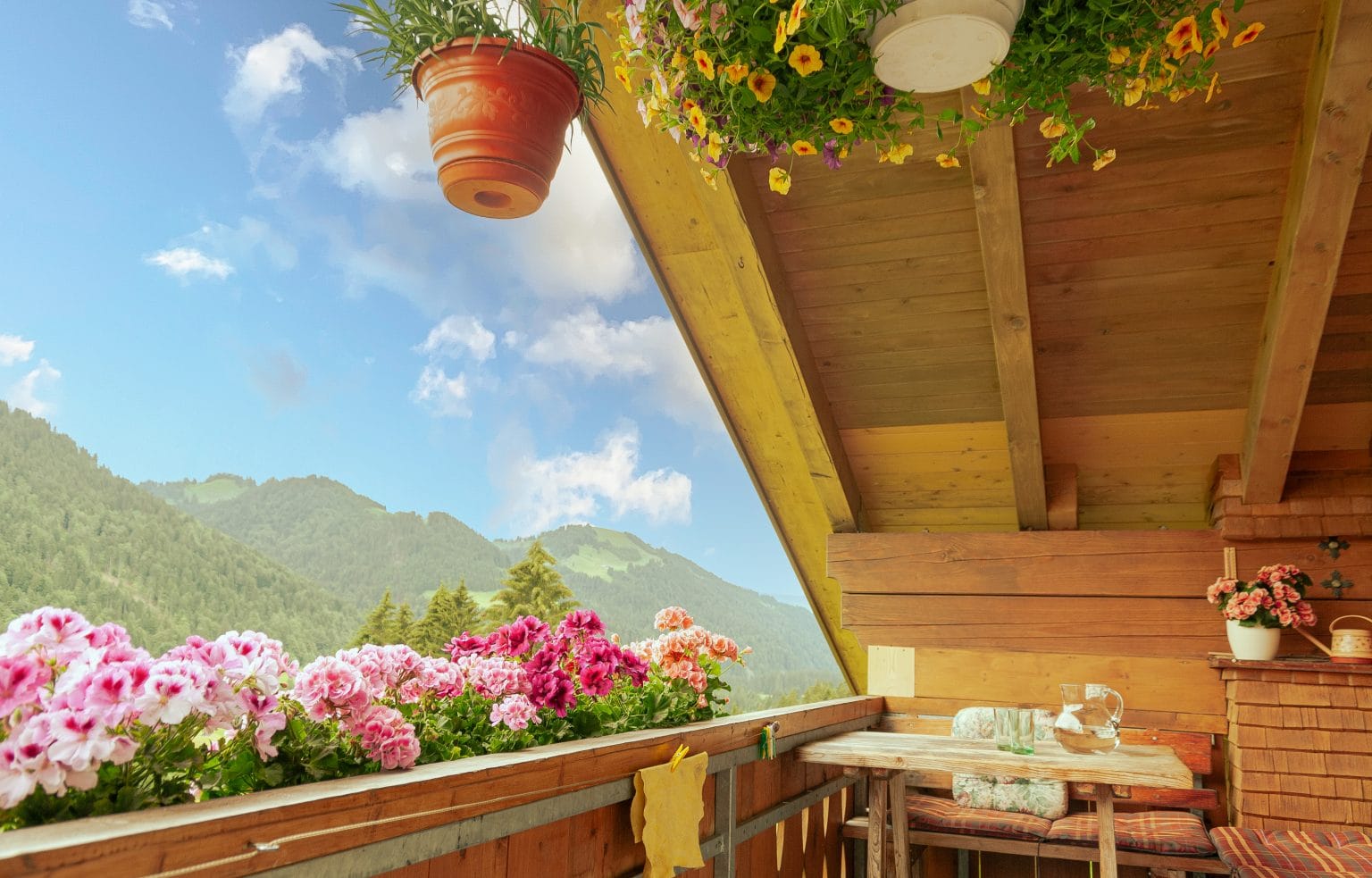 Ausblicke von einem Haus Anemone Balkon mit farbenprächtigen Blumen auf die umgebende Bergwelt und den Himmel.